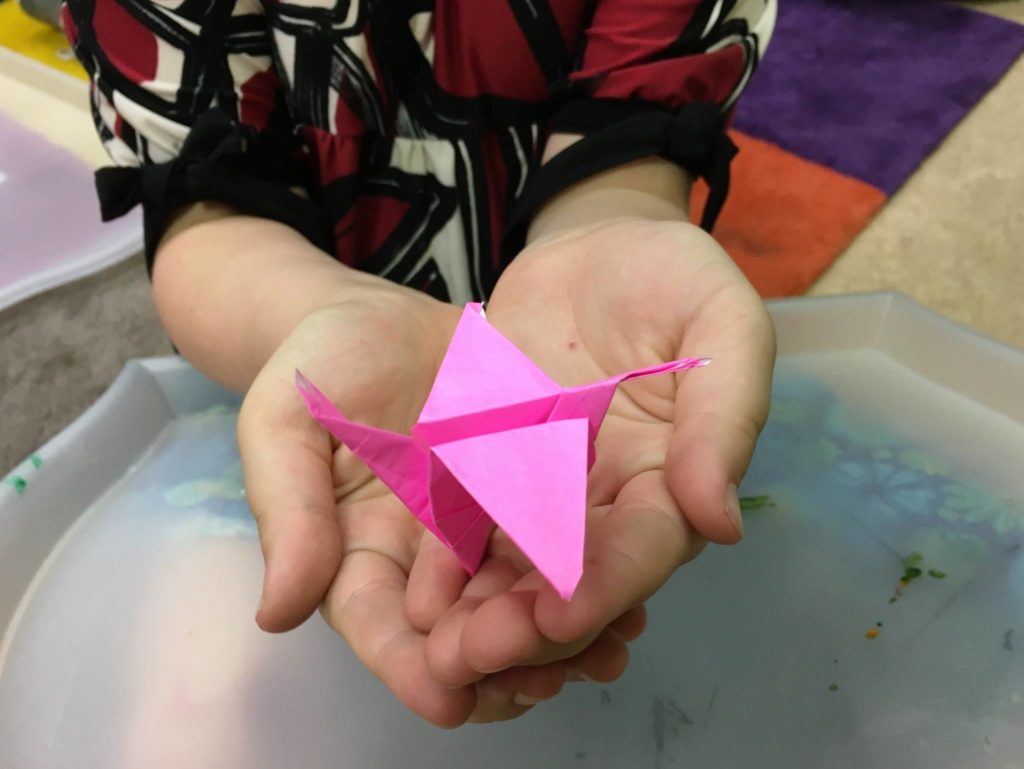 Child's hands holding paper crane