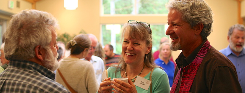 Three people smiling and talking in a crowd in the gathering area after service