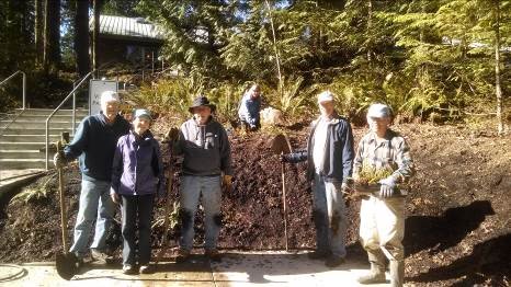 volunteers holding shovels after working in garden beds