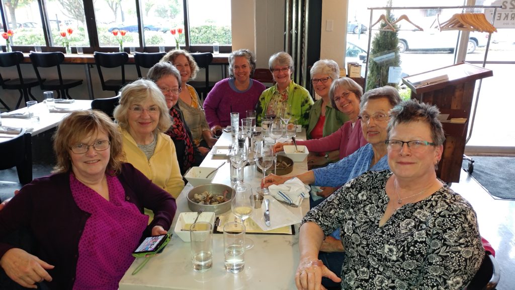 A group of women sitting at a restaurant table and smiling at the camera