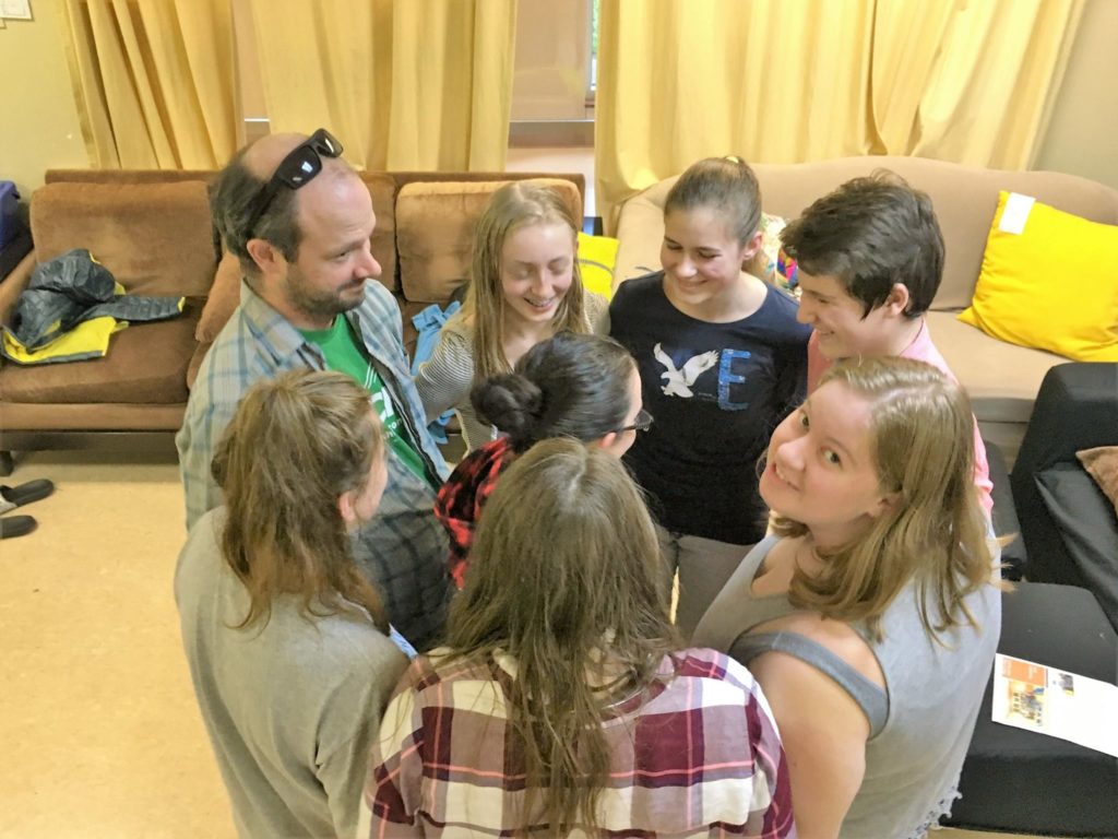 Children standing in a circle with an adult youth group leader