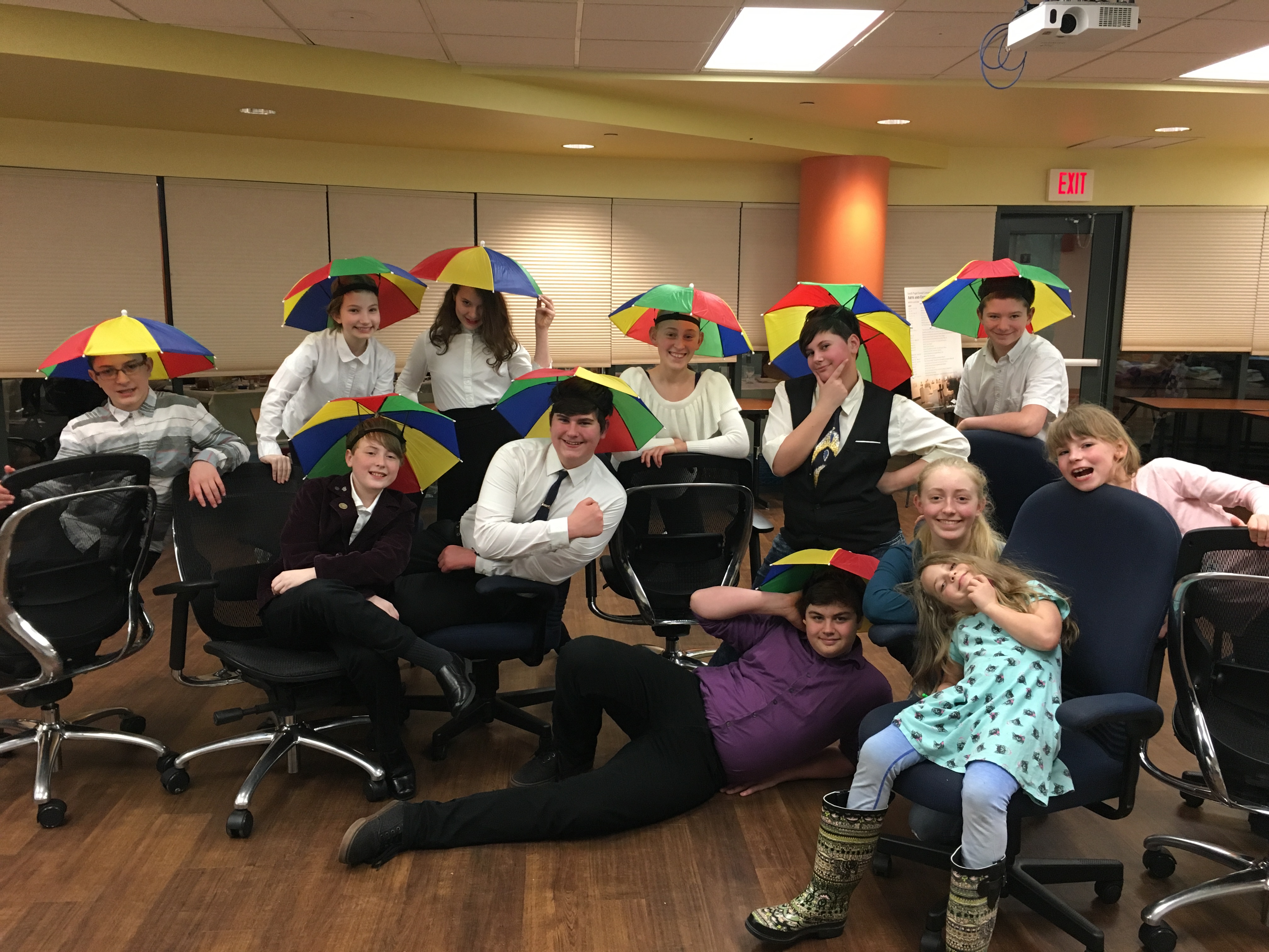 a goup of young people wearing rainbow umbrella hats and smiling