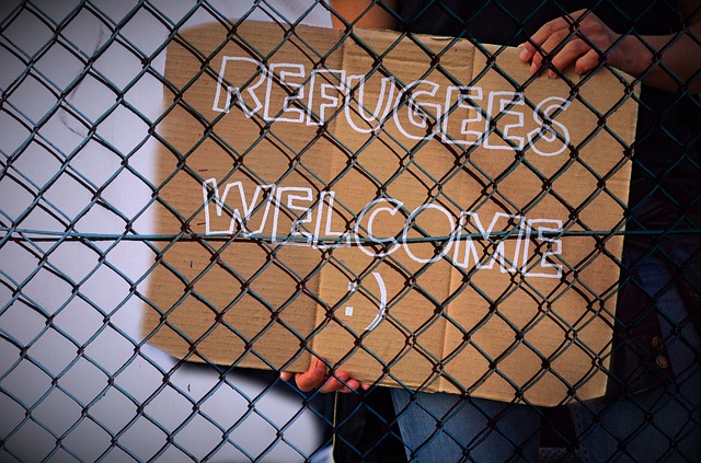 person holding a sign that says refugees welcome