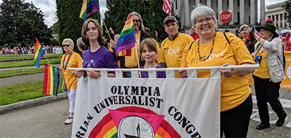 3 women and girls holding a banner leading the group in the pride parade
