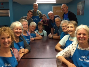 our community kitchen crew wearing aprons and sitting around a table