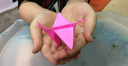 an origami crane in a child's hands